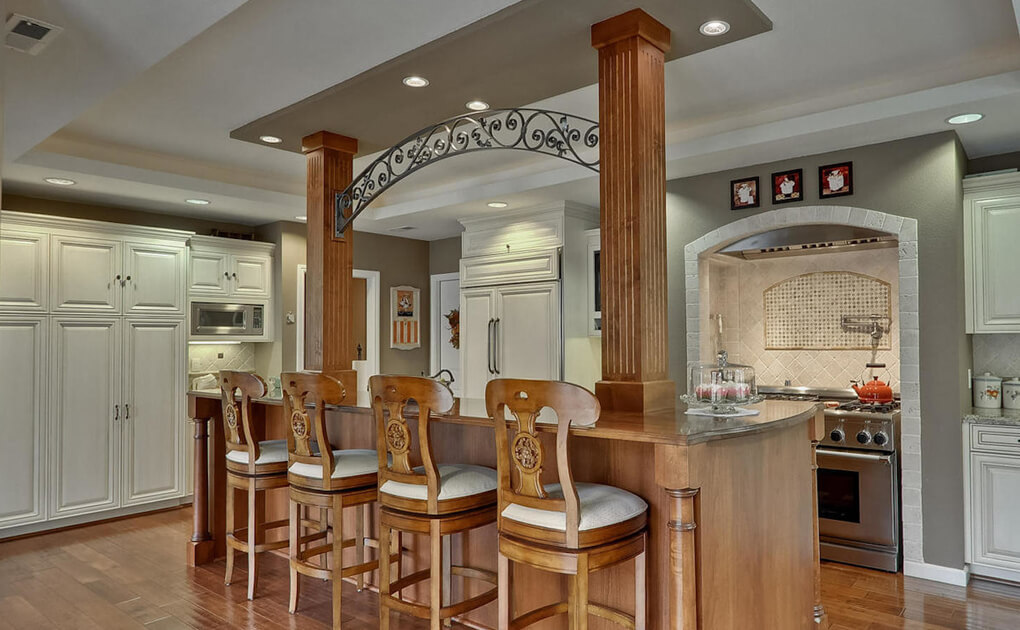 Luxury kitchen with white cabinets and wooden island with pillars